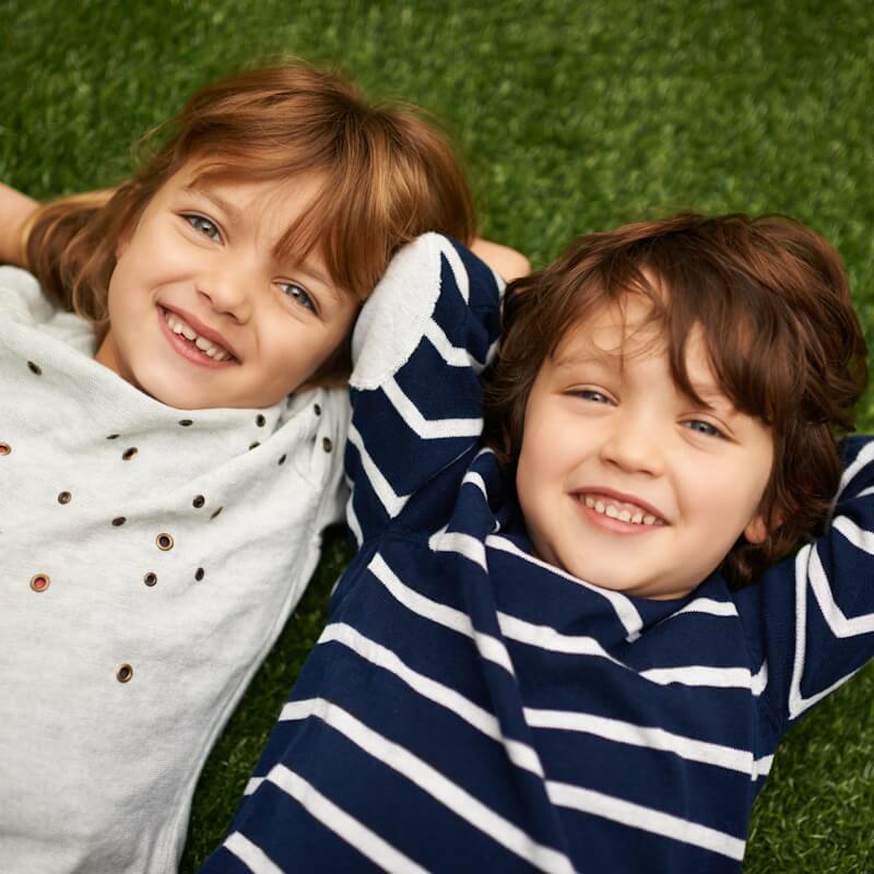 Sibling children laying in grass